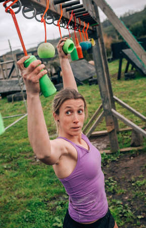 Female participant in an obstacle course doing suspension exercises