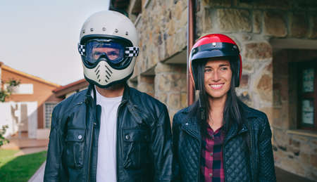Young couple posing with motorcycle helmets outdoors