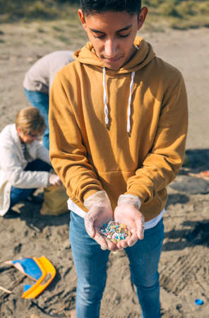 Young man showing microplastics collected on the beach