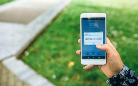 Woman hand holding smartphone with app update error text on the screen. English text in dialog box.の写真素材