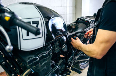 Mechanic repairing customized motorcycle by changing a fuse in the workshopの写真素材