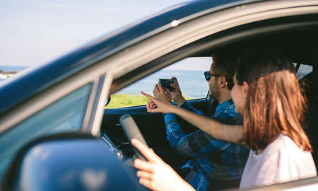 Couple traveling taking a picture of the landscape with the mobile from the car