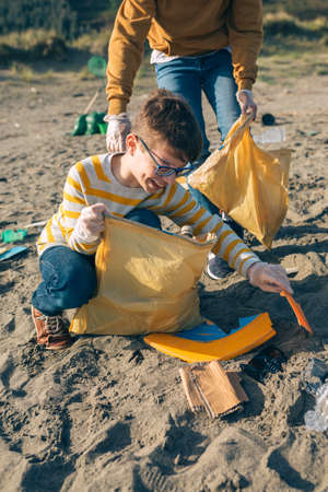 Young volunteers picking up trash on the beach