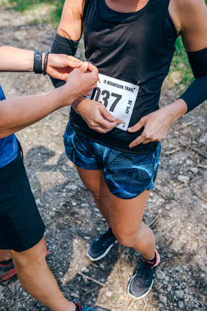 Girl placing the race number with the help of a teammateの写真素材