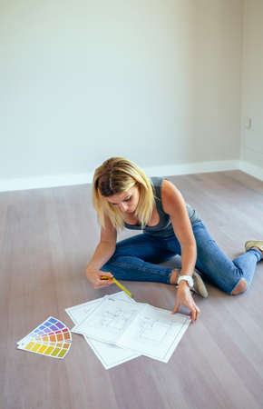 Girl looking house plans sitting on the floor