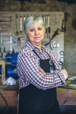 Senior female carpenter posing with crossed arms in his workshopの写真素材