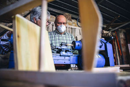 Senior man with protective mask working in a carpentry workshop