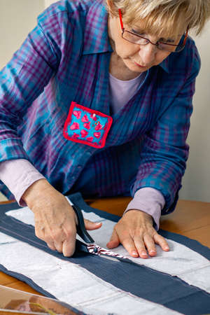 Dressmaker cutting a cloth to make a garment in her workshop