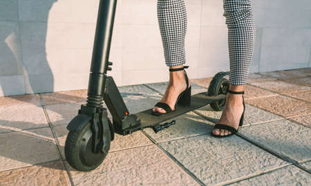 Unrecognizable businesswoman legs with e-scooter in the streetの写真素材