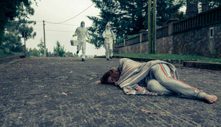 Man and woman in bacteriological protective suits running to help a woman passed out on the floorの写真素材