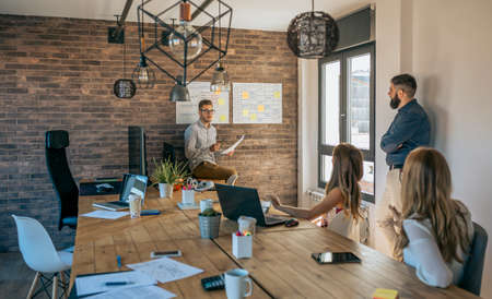 Young coach giving a talk to workers in a modern office