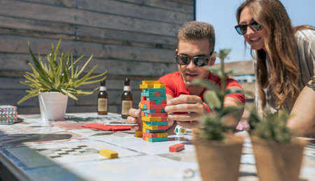 Man and woman playing with tower wooden on the terrace. Selective focus on tower in foreground
