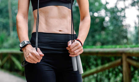Unrecognizable athlete woman posing with skipping rope in a park