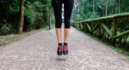 Feet of unrecognizable athlete woman jumping with skipping rope in a parkの写真素材