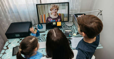 Top view of mother and children talking on video call with computer with grandmother