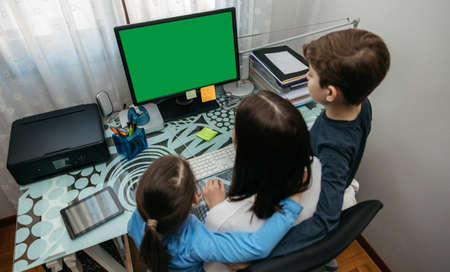 Top view of mother and children looking at computer screen at home