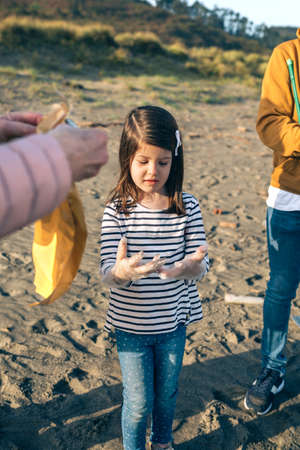Little girl with group of volunteers preparing to clean the beachの写真素材