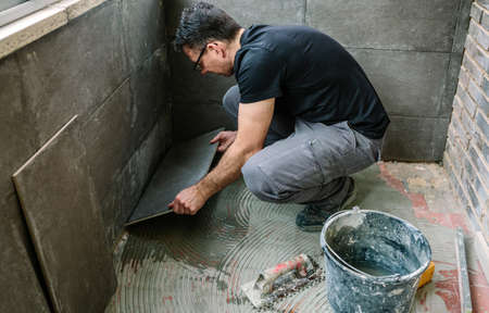 Workman laying a new tile floor on a terrace
