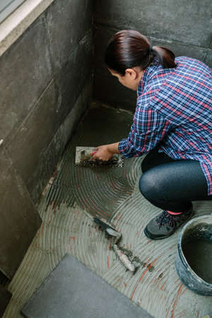 Top view of female mason laying a new tile floor on a terraceの写真素材