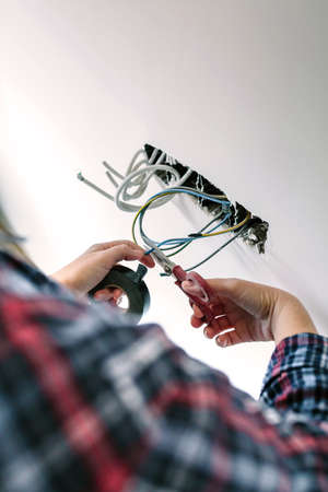 Unrecognizable female electrician cutting cables to the electrical installation of a houseの写真素材