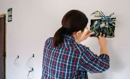 Unrecognizable female electrician working on the electrical installation of a houseの写真素材