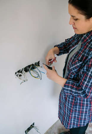 Female electrician cutting electrical tape to the electrical installation of a houseの写真素材