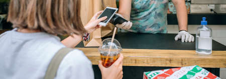 Young woman with mask paying with mobile a take away orderの写真素材