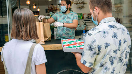 Young couple with mask picking up a take away food orderの写真素材