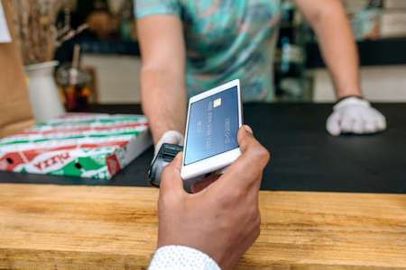 Unrecognizable young man with mask paying with mobile a take away food order