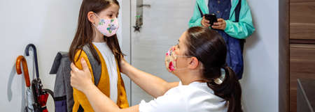 Mother advising her daughter on coronavirus precautions before going to schoolの写真素材