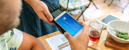 Closeup of unrecognizable customer paying the restaurant bill with a virtual mobile card