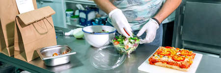 Unrecognizable cook in restaurant kitchen preparing takeaway ordersの写真素材