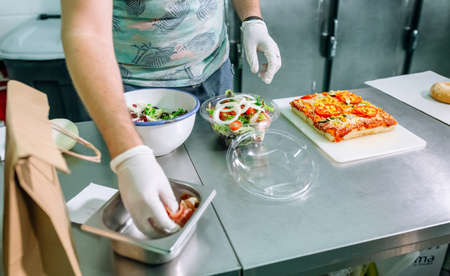 Unrecognizable cook in restaurant kitchen preparing takeaway ordersの写真素材