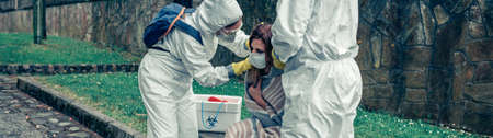 Doctors putting protective mask on woman infected by a virus outdoorsの写真素材