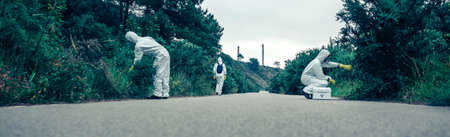 Group of people in bacteriological protection suits looking for samples on an empty roadの写真素材