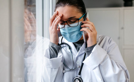 Sad and worried female doctor talking on the phone