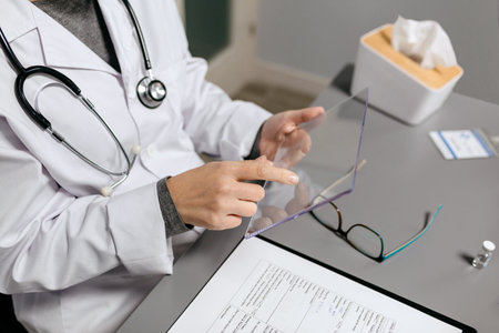 Unrecognizable female doctor working with transparent tablet in her office