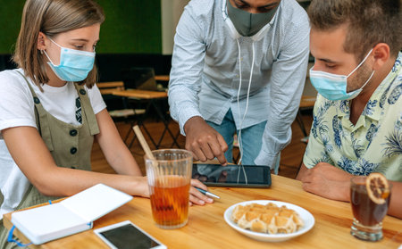Young people looking at the tablet sitting in a coffee shop