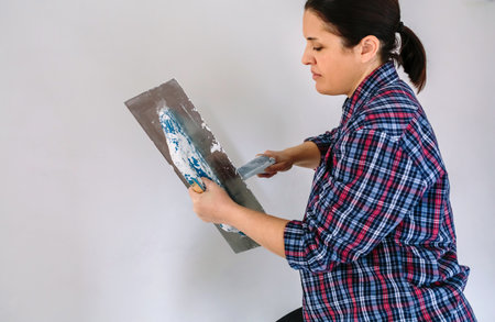 Female builder working picking plaster with spatulaの写真素材