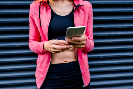 Portrait of unrecognizable female athlete posing with mobile phoneの写真素材