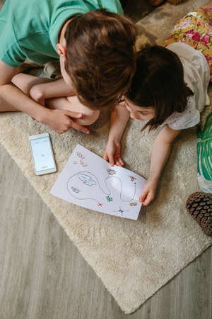Top view of unrecognizable kids playing treasure hunt at home on the carpet