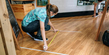 Coffee shop workers measuring floor marks to keep social distanceの写真素材