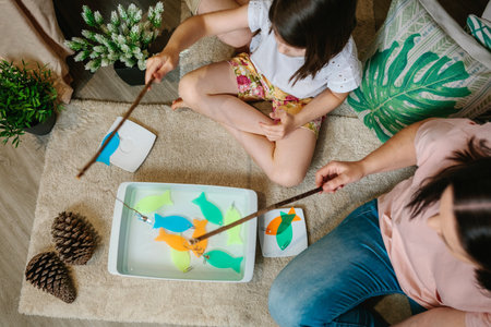 Top view of unrecognizable mother and daughter camping at home playing diy fishing gameの写真素材
