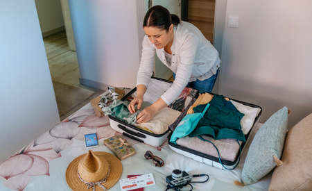 Woman preparing suitcase for summer holidays on the bedの写真素材