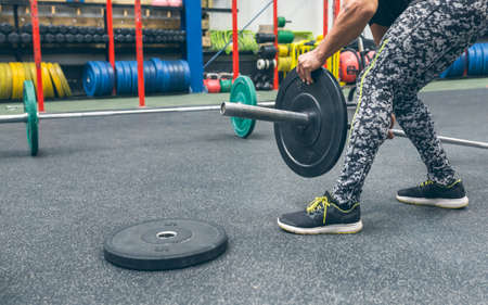 Unrecognizable man crouching changing the discs of the weightlifting barの写真素材