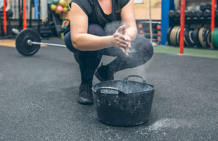 Unrecognizable woman applying magnesium to her hands to practice weightliftingの写真素材
