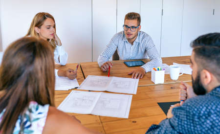 Businesspeople in a work meeting looking at construction drawings of a house