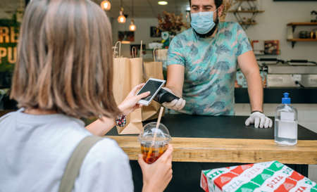 Young woman with mask paying with mobile a take away orderの写真素材