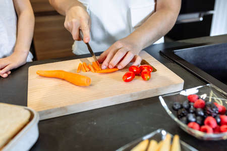 Unrecognizable woman preparing healthy snack with carrot and cherry tomatoesの写真素材