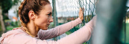 Serious young sportswoman with boxer braids leaning on a metal fenceの写真素材